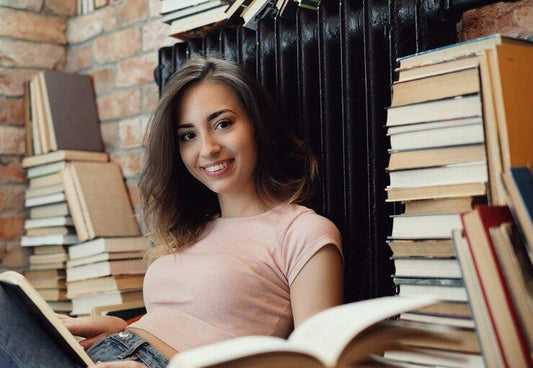 Young woman reading self-help and fiction books surrounded by book stacks in Sri Lanka bookstore
