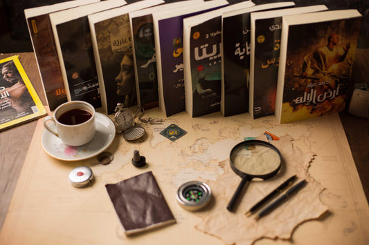 Arabic books, a cup of tea, pocket watch, compass, magnifying glass, and pens on a vintage world map